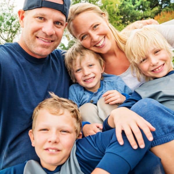 A mother, father, and three young sons smiling and enjoying time together.