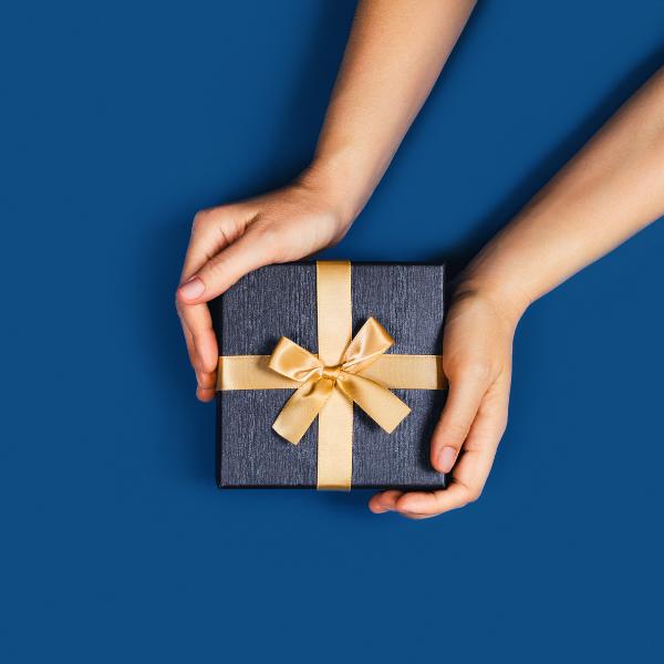 Hands holding a gift box on a blue background