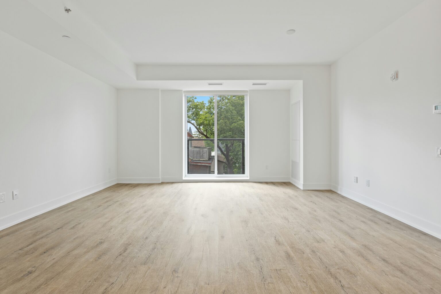 Empty room with honey colored floors and white walls