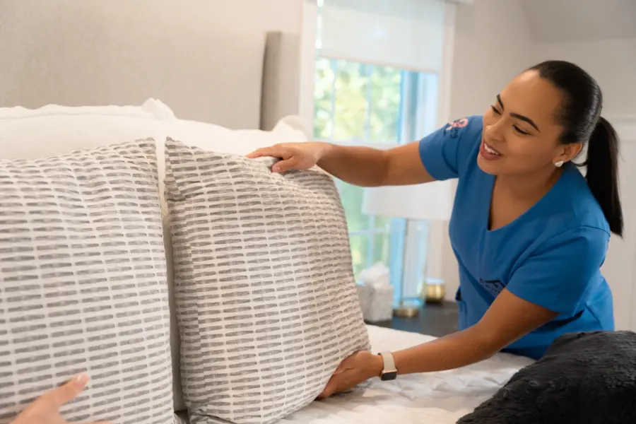 Airbnb Cleaning 3 A Family Cleaners team member setting striped decorative pillows on a made bed