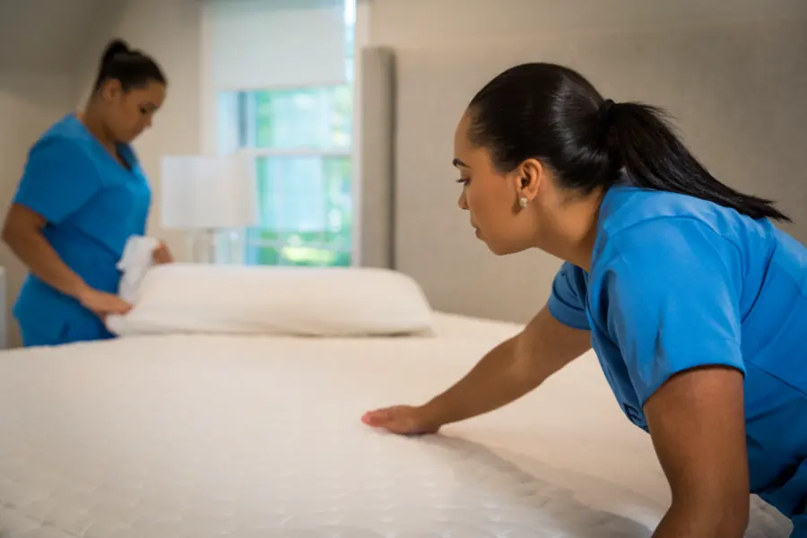 Airbnb Cleaning 2 A Family Cleaners team member smoothing a fresh white sheet over a mattress