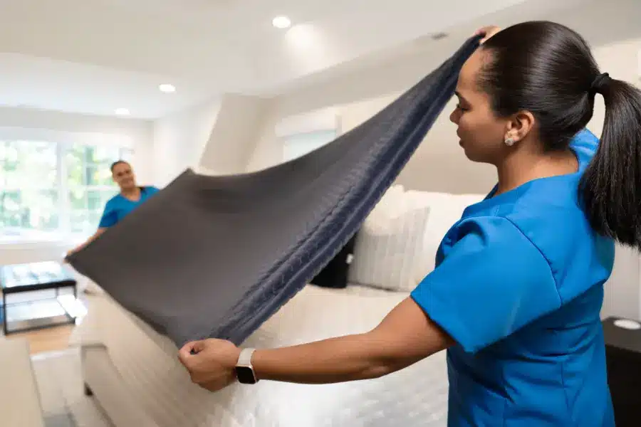 Airbnb Cleaning 4 A Family Cleaners team member laying a gray throw across the end of a bed