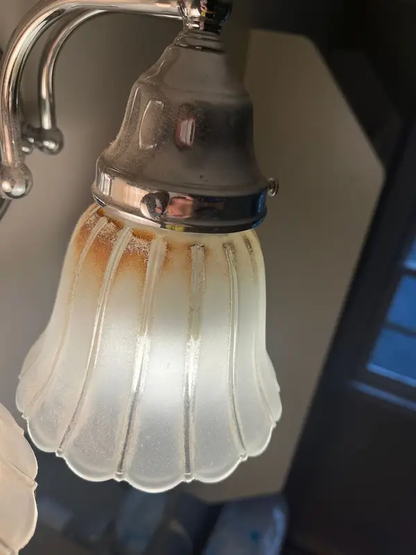 Frosted glass bathroom light shade with orange stains before deep cleaning