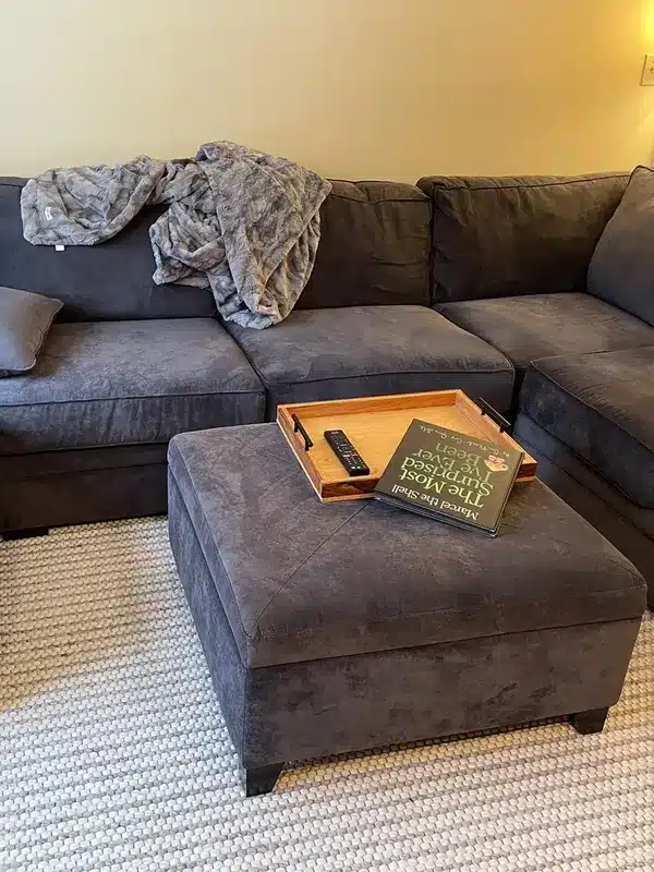 Gray sectional with a blanket piled on it before cleaning, Simsbury, CT