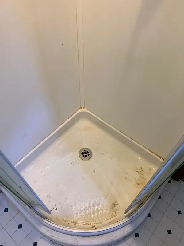 Corner shower pan with brown stains and soap scum before cleaning, Glastonbury, CT