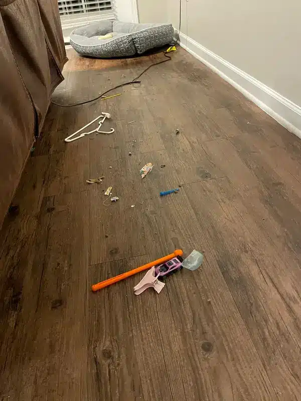 Wood-look floor scattered with toys, a hanger and debris before cleaning, Simsbury, CT