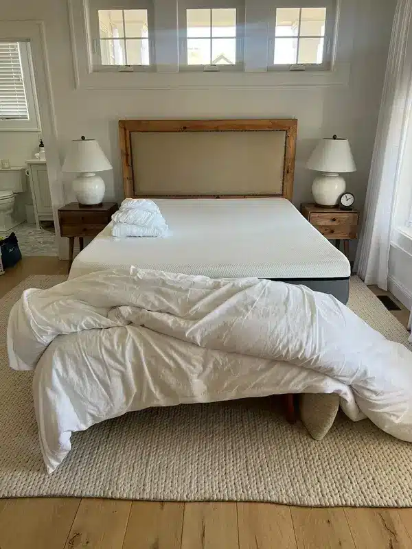 Unmade bed with the duvet falling to the floor before cleaning, Suffield, CT