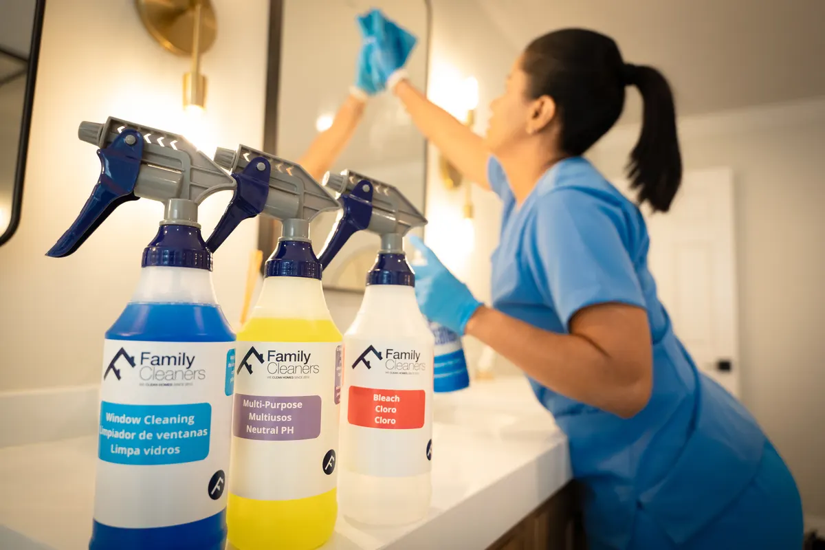 Office Cleaning Services 2 Family Cleaners branded spray bottles on a counter while a team member wipes a mirror