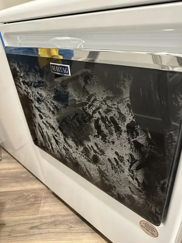Glass lid of a new appliance covered in white construction dust