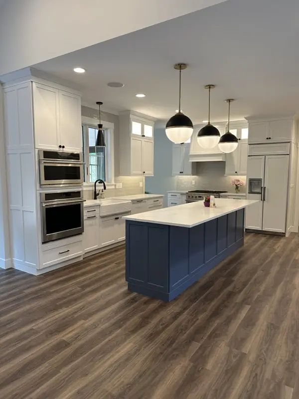 The same kitchen finished, with a clear navy island, white cabinets and clean floors