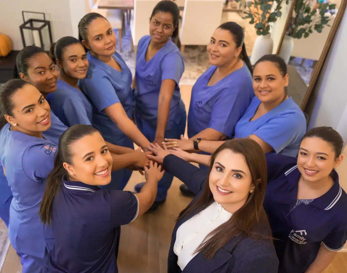 The Family Cleaners team with hands joined in a circle, smiling up at the camera