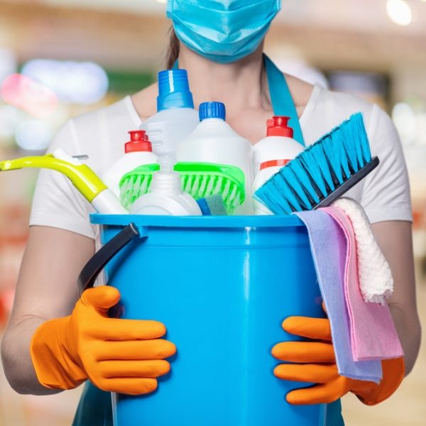 A professional house cleaner holding a bucket of cleaning supplies.