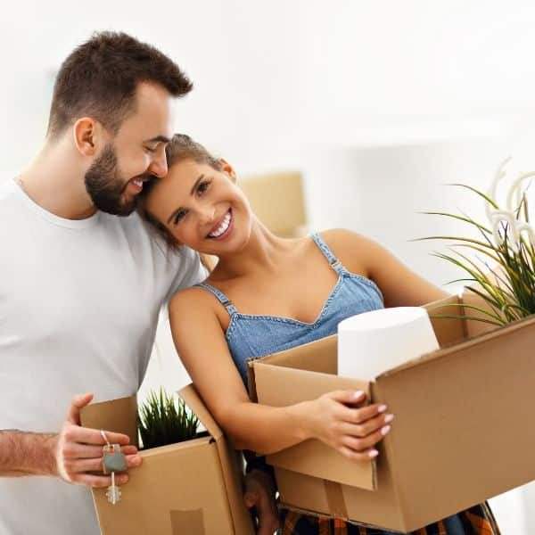 A happy young couple holding cardboard moving boxes.